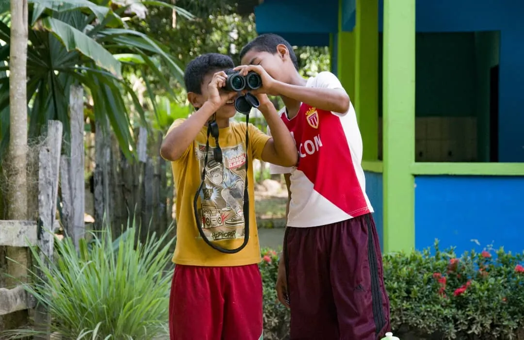 Dos niños mirando con binoculares durante una salida de observación